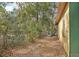 View of the side yard shows space between house and fence with leaves at 303 Grand Ave, Brooksville, FL 34604