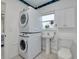 Compact bathroom with a stacked washer and dryer, pedestal sink, and white tiled floors at 305 6Th Sw Ave, Largo, FL 33770