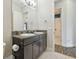 Bathroom with dark vanity, double sinks, a large mirror and wood look floors in the hallway at 32484 Worden Pass, Wesley Chapel, FL 33543