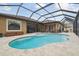 A beautiful kidney-shaped pool is surrounded by a screened-in lanai and travertine pavers at 32484 Worden Pass, Wesley Chapel, FL 33543