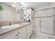 Well-lit bathroom featuring double sinks, a walk-in shower with glass doors, and tiled floors at 37508 Gill Ave, Zephyrhills, FL 33541