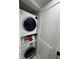 A compact laundry closet featuring a stacked washer and dryer unit with detergent and cleaning supplies neatly arranged at 400 Island Way # 612, Clearwater Beach, FL 33767