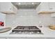 Kitchen cooktop with stainless steel vent hood and white backsplash and countertops at 618 Manns Harbor Dr, Apollo Beach, FL 33572