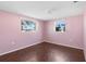 Cozy bedroom with wood floors, windows that bring in natural light, and pink walls at 6840 Mesa Verde St, Port Richey, FL 34668