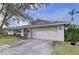 Spacious two-car garage with a concrete driveway, neatly landscaped yard, and outdoor lighting fixtures at 6880 Greenbrier Dr, Seminole, FL 33777