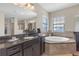 Elegant bathroom features a soaking tub, granite countertop, and a large mirror reflecting the bright, neutral decor at 8414 Eagle Brook Dr, Land O Lakes, FL 34638