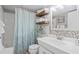 Bright bathroom featuring tiled walls, wood shelves, and a shower with a patterned curtain at 10355 Paradise Blvd # 909, Treasure Island, FL 33706