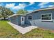 A concrete patio extends from the blue house into the green backyard at 1119 77Th N St, St Petersburg, FL 33710