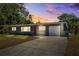 Charming single Gathering home featuring a red door, attached garage, and well-maintained lawn at sunset at 1119 77Th N St, St Petersburg, FL 33710