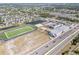 Wide aerial view of a neighborhood with modern school, sports fields, and recreational ponds at 11517 Weston Course Loop, Riverview, FL 33579