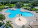 Aerial view of a uniquely-shaped community pool with splash features, lounge seating, and a playground nearby at 11517 Weston Course Loop, Riverview, FL 33579