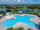 Aerial view of a lakefront community pool with lounge chairs, a sandy area, and covered seating at 11517 Weston Course Loop, Riverview, FL 33579