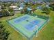 Aerial view of the fenced community tennis courts surrounded by lush greenery at 11517 Weston Course Loop, Riverview, FL 33579