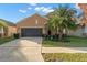 This house is painted tan and features a black two-car garage and manicured lawn at 11720 Winterset Cove Dr, Riverview, FL 33579