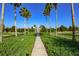 Entrance to a neighborhood featuring a sidewalk, green hedges, and palm trees for scenic appeal at 12729 Bramfield Dr, Riverview, FL 33579