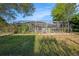 Backyard with a screened pool enclosure bordered by lush vegetation at 1559 Overland Dr, Spring Hill, FL 34608