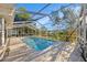 Sparkling pool inside a screened enclosure with lush landscaping and clear blue sky at 1559 Overland Dr, Spring Hill, FL 34608