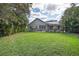 Expansive backyard featuring lush green grass, privacy landscaping, and a screened lanai perfect for outdoor relaxation at 2981 Northfield Dr, Tarpon Springs, FL 34688