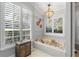 Bright bathroom featuring a soaking tub, large windows with plantation shutters, and a unique light fixture at 2981 Northfield Dr, Tarpon Springs, FL 34688
