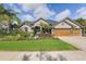 Beautiful one-story home featuring a lush front yard, tropical plants, and a spacious driveway at 2981 Northfield Dr, Tarpon Springs, FL 34688