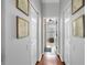 Hallway with hardwood floors and decorative framed map prints leading to a bathroom with plantation shutters at 2981 Northfield Dr, Tarpon Springs, FL 34688