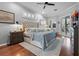 Beautiful main bedroom with a padded headboard, hardwood floors, ceiling fan, and natural light from plantation shutters at 2981 Northfield Dr, Tarpon Springs, FL 34688