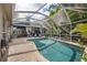 Inviting screened-in pool with brick patio, outdoor seating, and lush tropical landscaping creating a private oasis at 2981 Northfield Dr, Tarpon Springs, FL 34688