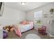 Cozy bedroom with a colorful bed, a fluffy white rug, a charming pink rocking chair, and natural light from the window at 3224 Fresno Pl, Zephyrhills, FL 33541
