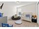 Bright bedroom featuring neutral walls, carpeted floors, a cozy beanbag, and a gray crib with a patterned baby blanket at 3224 Fresno Pl, Zephyrhills, FL 33541