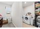 Well-lit laundry room with modern white washer and dryer, storage shelves, and a window for natural light at 3224 Fresno Pl, Zephyrhills, FL 33541