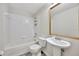A clean bathroom featuring a white tiled shower-tub combo, a pedestal sink, and a gold-framed mirror at 3870 Island Way, St Petersburg, FL 33705