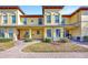 Inviting yellow townhouse with manicured landscaping, brick walkway, and covered porch at 3870 Island Way, St Petersburg, FL 33705