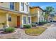 Welcoming townhouse exterior with an orange front door, and well-maintained landscaping at 3870 Island Way, St Petersburg, FL 33705