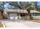 Charming single-story home featuring a light green exterior, well-manicured lawn and a bright pink front door at 4407 Parnell Dr, Sarasota, FL 34232