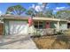 Inviting home with a freshly painted light green facade, a manicured front garden, and an American flag at 4407 Parnell Dr, Sarasota, FL 34232