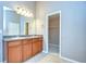 Bathroom with double sink vanity, a large mirror, modern lighting, and closet access at 5704 Kingletsound Pl, Lithia, FL 33547