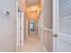 Bright hallway leading to bedrooms with carpet flooring, neutral paint, and white doors at 5704 Kingletsound Pl, Lithia, FL 33547