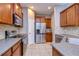 Well-lit kitchen featuring stainless steel appliances, granite counters, tile flooring, and wooden cabinetry at 5704 Kingletsound Pl, Lithia, FL 33547