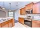 Open kitchen showcasing stainless steel appliances, wooden cabinets, tile backsplash, and breakfast bar at 5704 Kingletsound Pl, Lithia, FL 33547
