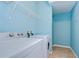 Laundry room with washer, dryer and wall-mounted shelves for storage, and light blue paint at 5704 Kingletsound Pl, Lithia, FL 33547