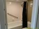 Bathroom featuring a tiled tub, shower with safety bar and black patterned curtain at 6009 Sea Ranch Dr # 307, Hudson, FL 34667