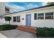 Eye-level view of the front of a white home with a bright blue front door, green bushes, and brick steps at 735 Snell Isle Ne Blvd, St Petersburg, FL 33704