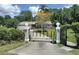 Gated entry of a home with a meticulously maintained lawn and mature landscaping offering privacy at 8946 Old Pasco Rd, Wesley Chapel, FL 33544