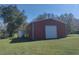 A wide shot of a storage building with a roll up door in a large, well-maintained grassy area at 8946 Old Pasco Rd, Wesley Chapel, FL 33544