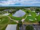 Beautiful aerial view of the community golf course featuring lush greens and a serene lake at 10416 Moshie Ln, San Antonio, FL 33576