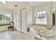 This bathroom features a tub under a window with patterned curtains, tiled floors, and neutral walls at 10416 Moshie Ln, San Antonio, FL 33576