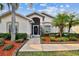 Welcoming front entrance featuring manicured landscaping, palm trees, and decorative accents at 10416 Moshie Ln, San Antonio, FL 33576