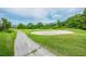 View of a golf course with a sand trap, green, and cart path amidst lush greenery and trees at 10416 Moshie Ln, San Antonio, FL 33576