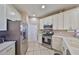 Bright kitchen features white cabinetry, stainless steel appliances, and tile flooring at 1154 Jameson Greens N Dr # 20, Sun City Center, FL 33573