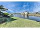 A lush green lawn leads to a serene lake view, showcasing the backyard's peaceful setting at 1335 Jumana Loop, Apollo Beach, FL 33572